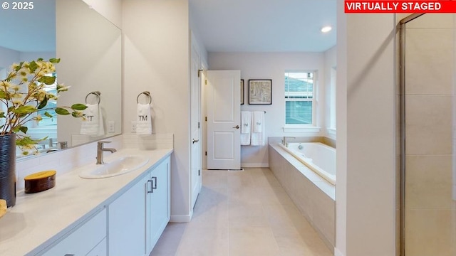 bathroom with tile patterned flooring, vanity, and a relaxing tiled tub