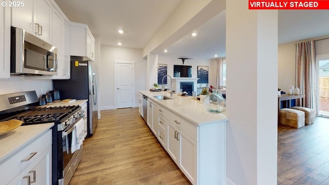 kitchen featuring sink, a healthy amount of sunlight, stainless steel appliances, white cabinets, and light wood-type flooring