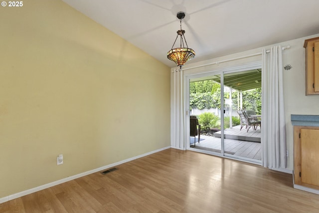unfurnished dining area with light wood-type flooring, baseboards, and vaulted ceiling