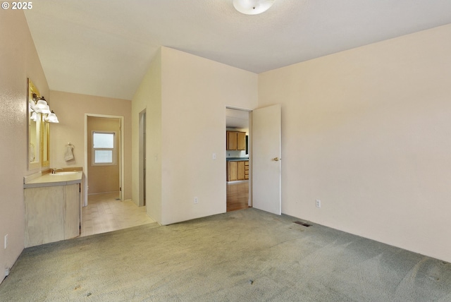 unfurnished bedroom featuring a sink, light carpet, and connected bathroom