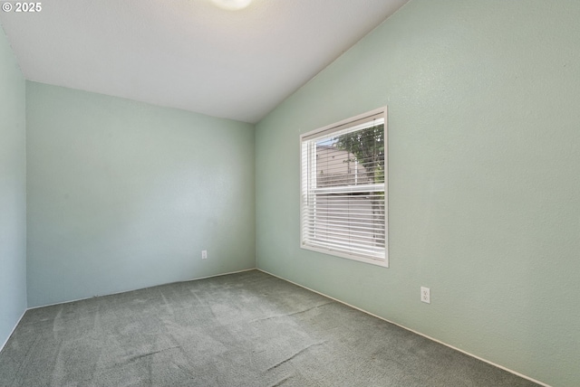 carpeted spare room with lofted ceiling