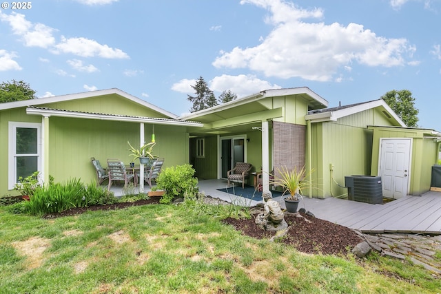 rear view of house with cooling unit, a patio, and a lawn