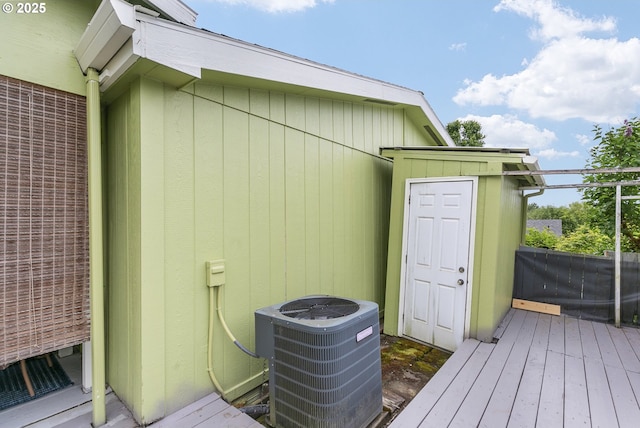 wooden deck with central air condition unit, a storage unit, and an outdoor structure