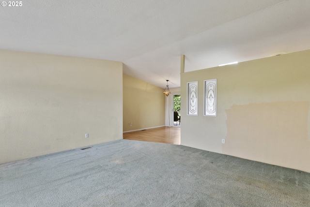 spare room featuring carpet and lofted ceiling