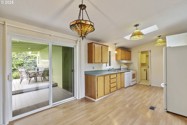 kitchen featuring freestanding refrigerator, electric range, light wood-style flooring, a skylight, and a sink