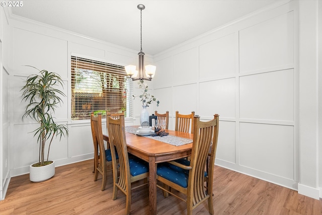 dining area featuring crown molding, light hardwood / wood-style floors, and an inviting chandelier