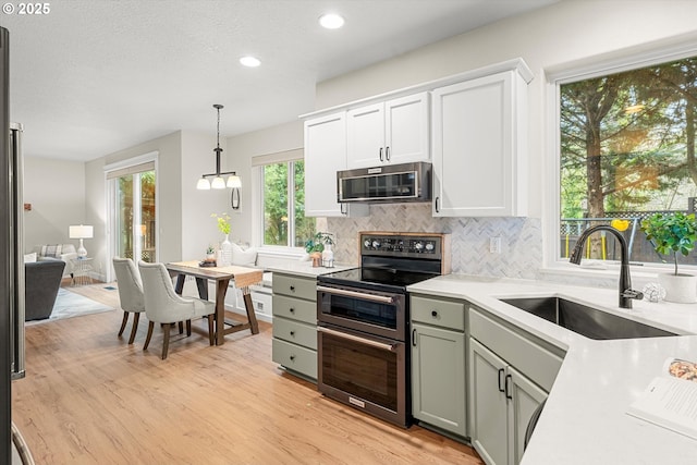 kitchen featuring backsplash, sink, electric stove, pendant lighting, and light hardwood / wood-style floors