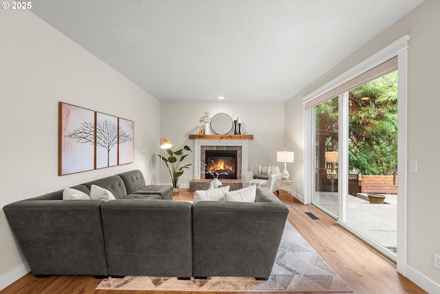 living room featuring a tile fireplace and light hardwood / wood-style floors