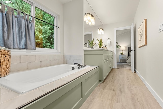 bathroom featuring a bathtub, vanity, wood-type flooring, and an inviting chandelier