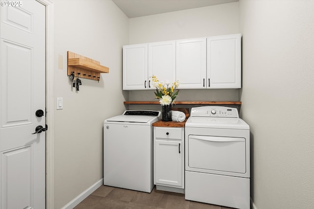 laundry room featuring washer and clothes dryer and cabinets