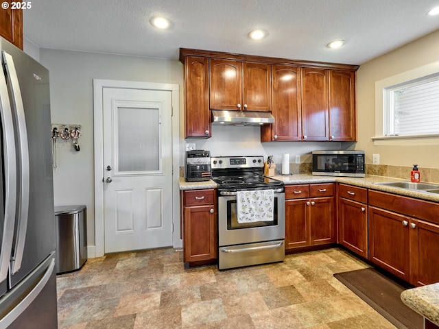 kitchen with a textured ceiling, stainless steel appliances, and sink