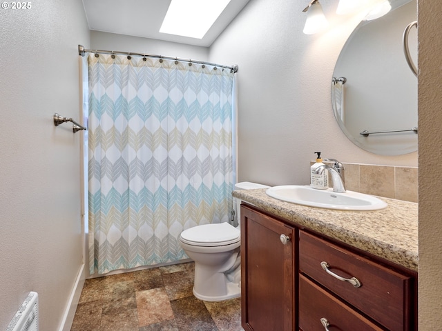 bathroom with walk in shower, a skylight, vanity, and toilet