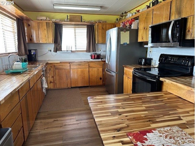 58474 Old Lake Rd, Christmas Valley, OR 97641 - kitchen featuring stainless steel microwave, black range with electric cooktop, brown cabinetry, a sink, and wood finished floors
