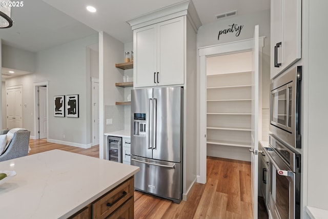1825 NW Tanner Ct, Camas, WA 98607 - kitchen with appliances with stainless steel finishes, open shelves, white cabinets, light wood-style floors, and wine cooler