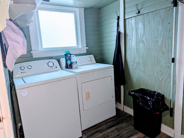 laundry room featuring dark wood-type flooring, washer and clothes dryer, and wooden walls