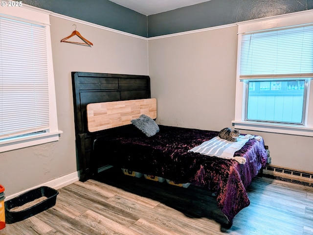 bedroom with hardwood / wood-style flooring and a baseboard heating unit