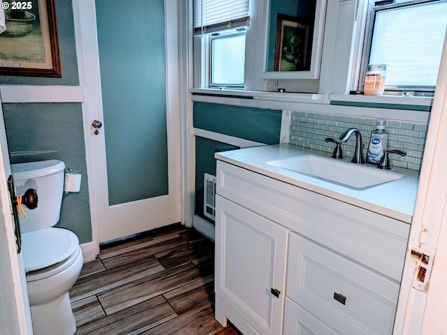 bathroom featuring tasteful backsplash, vanity, hardwood / wood-style floors, and toilet