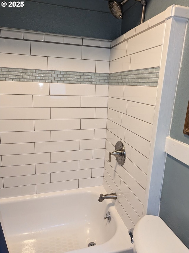 bathroom featuring tiled shower / bath combo and toilet