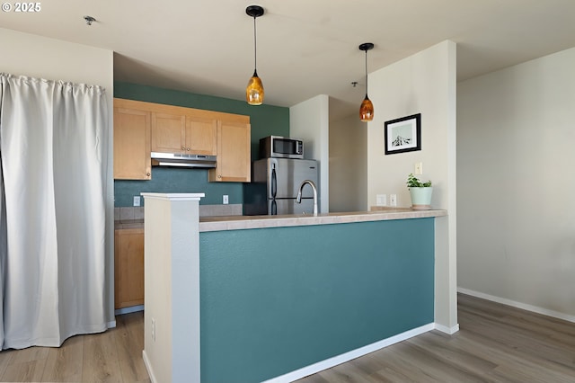410 NW Uptown Ter Unit 3-B, Portland, OR 97210 - kitchen with appliances with stainless steel finishes, under cabinet range hood, light wood-type flooring, light brown cabinets, and pendant lighting