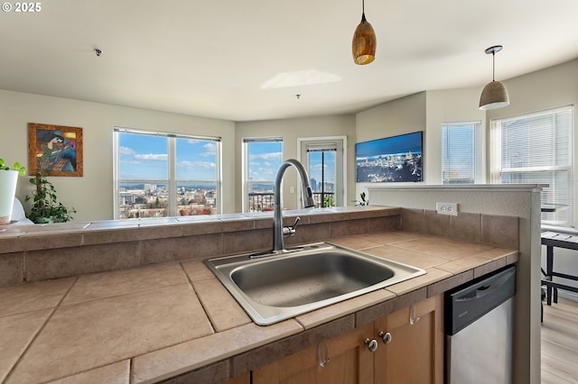410 NW Uptown Ter Unit 3-B, Portland, OR 97210 - kitchen featuring stainless steel dishwasher, a sink, pendant lighting, brown cabinets, and tile countertops