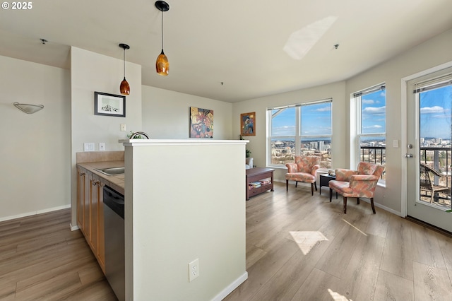 410 NW Uptown Ter Unit 3-B, Portland, OR 97210 - kitchen with dishwasher, light wood-style floors, baseboards, decorative light fixtures, and light countertops