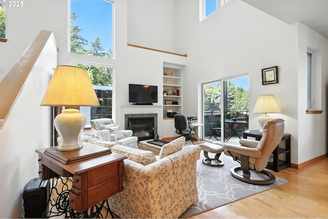 2024 SW Howards Way, Portland, OR 97201 - living area with built in shelves, a high ceiling, wood finished floors, and a glass covered fireplace