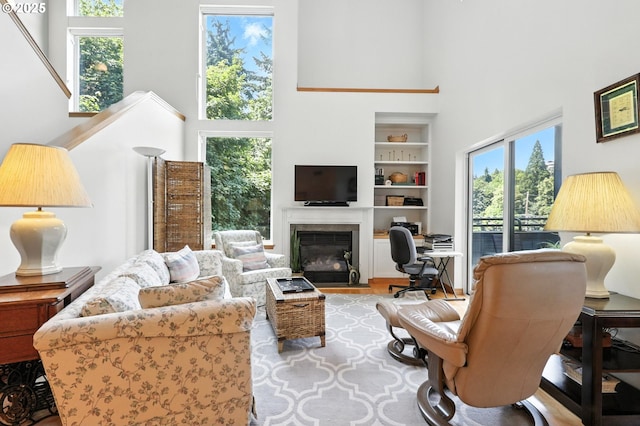 2024 SW Howards Way, Portland, OR 97201 - living area with a high ceiling, built in shelves, a desk, a fireplace with flush hearth, and wood finished floors