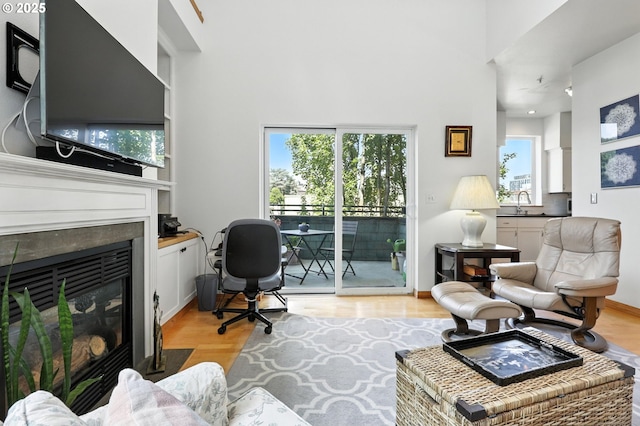 2024 SW Howards Way, Portland, OR 97201 - living room featuring a glass covered fireplace, plenty of natural light, a towering ceiling, and light wood-style floors