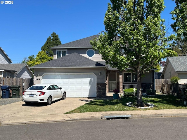 traditional home featuring an attached garage, fence, concrete driveway, a front yard, and roof with shingles
