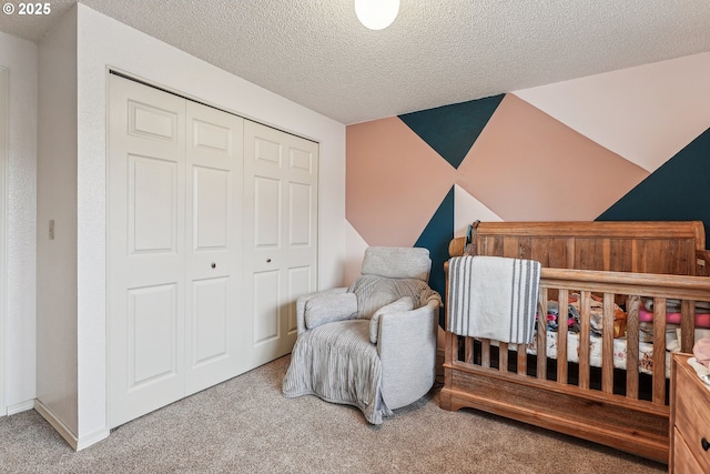 carpeted bedroom with a textured ceiling, a closet, and a crib