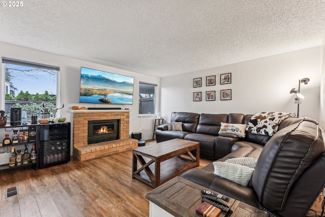 living room with a brick fireplace, a textured ceiling, and hardwood / wood-style floors