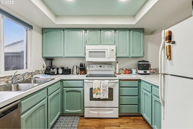 kitchen featuring a tray ceiling, sink, white appliances, and green cabinetry