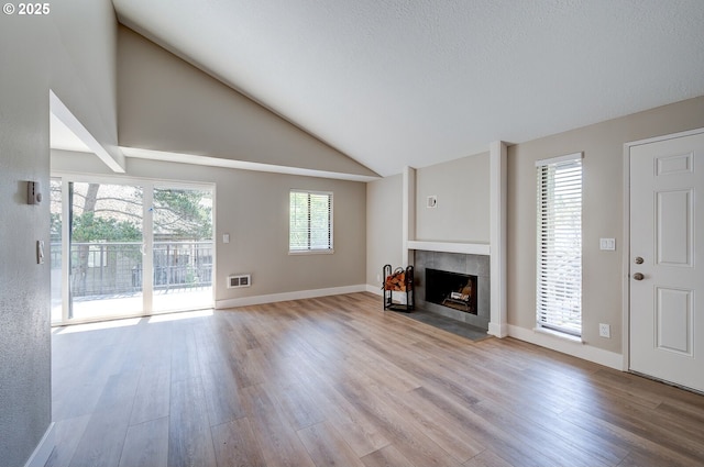 56 Galen St, Lake Oswego, OR 97035 - unfurnished living room featuring wood finished floors, a tiled fireplace, lofted ceiling, and baseboards