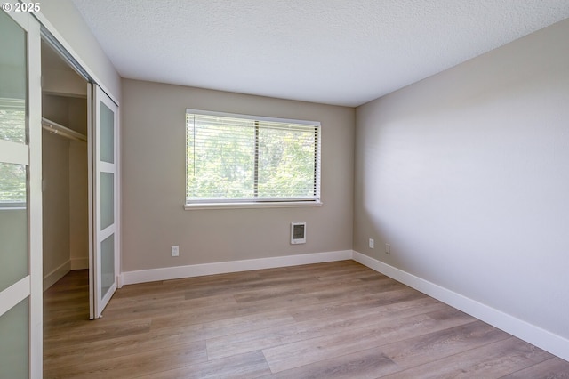 56 Galen St, Lake Oswego, OR 97035 - unfurnished bedroom with light wood finished floors, heating unit, baseboards, a textured ceiling, and a closet