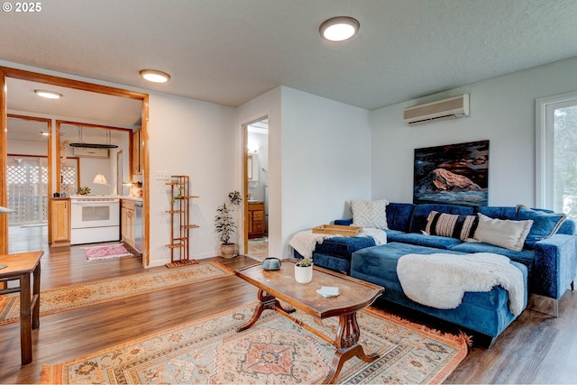 living area with a textured ceiling, a wall mounted AC, baseboards, and wood finished floors