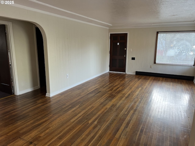 empty room with dark wood-style floors, arched walkways, a baseboard radiator, ornamental molding, and baseboards