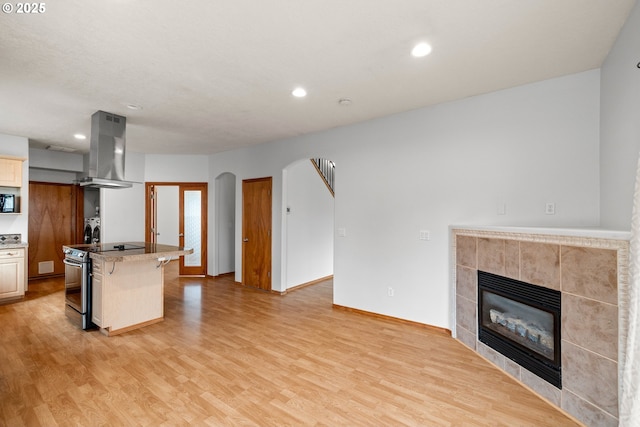 651 NE Anderson Rd, Gresham, OR 97030 - kitchen featuring island range hood, stainless steel range with electric cooktop, light wood-type flooring, a tile fireplace, and recessed lighting