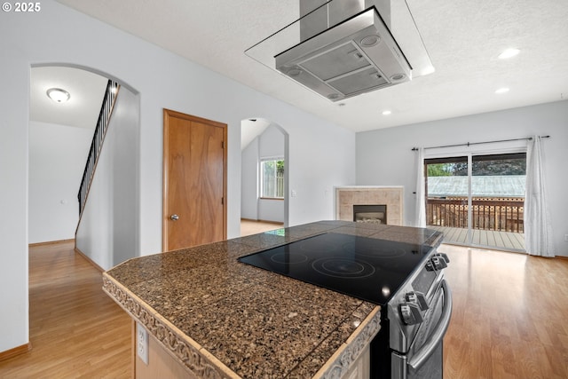 651 NE Anderson Rd, Gresham, OR 97030 - kitchen featuring stainless steel electric stove, arched walkways, tile countertops, light wood finished floors, and open floor plan