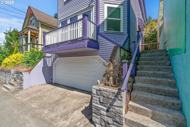 3147 SE Belmont St, Portland, OR 97214 - view of home's exterior with a garage, a balcony, stairs, and driveway
