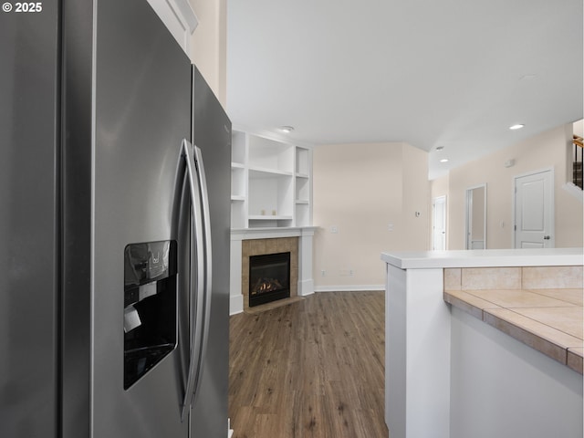 kitchen with stainless steel refrigerator with ice dispenser, wood-type flooring, and a fireplace