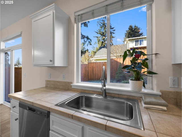 kitchen featuring white cabinetry, sink, tile countertops, and stainless steel dishwasher