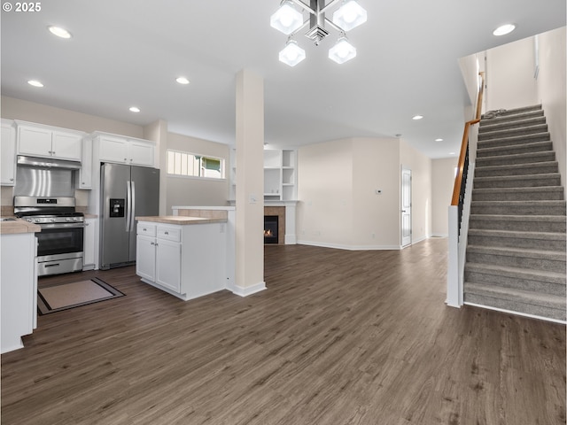 kitchen with dark wood-type flooring, stainless steel appliances, a kitchen breakfast bar, and white cabinets