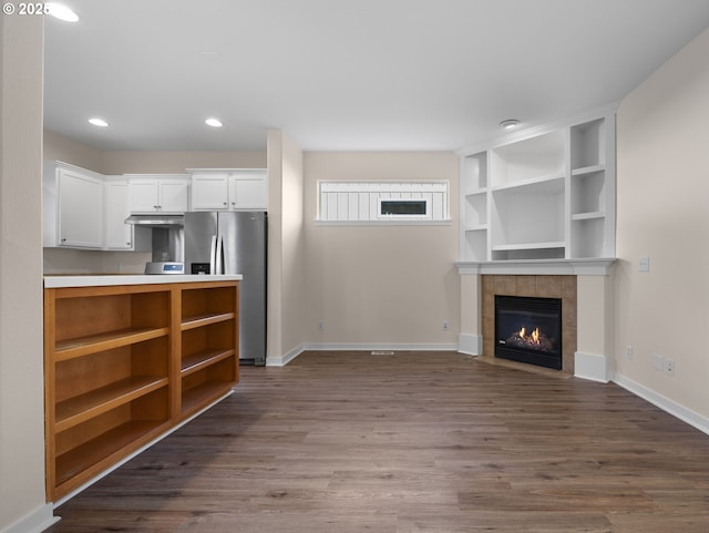 kitchen with hardwood / wood-style flooring, a fireplace, stainless steel fridge, and white cabinets