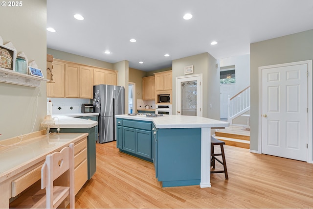 kitchen featuring freestanding refrigerator, blue cabinetry, light brown cabinetry, light countertops, and built in microwave