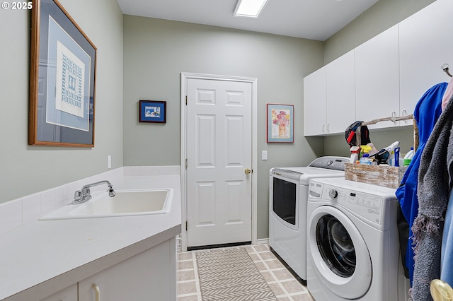 clothes washing area with a sink, cabinet space, and washing machine and dryer