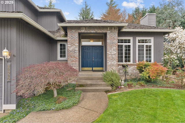 doorway to property featuring a yard, brick siding, and a chimney