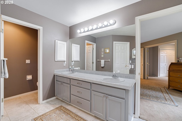 bathroom with double vanity, baseboards, a sink, and toilet