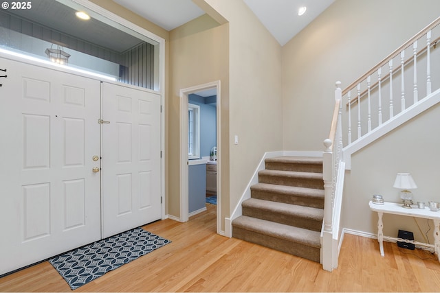 foyer entrance featuring wood finished floors, baseboards, and stairway