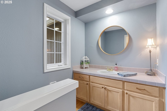 bathroom with a textured wall, vanity, and wood finished floors