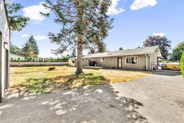 9304 NE 96th St, Vancouver, WA 98662 - view of front of house featuring board and batten siding, a fenced backyard, a chimney, a shingled roof, and an outbuilding